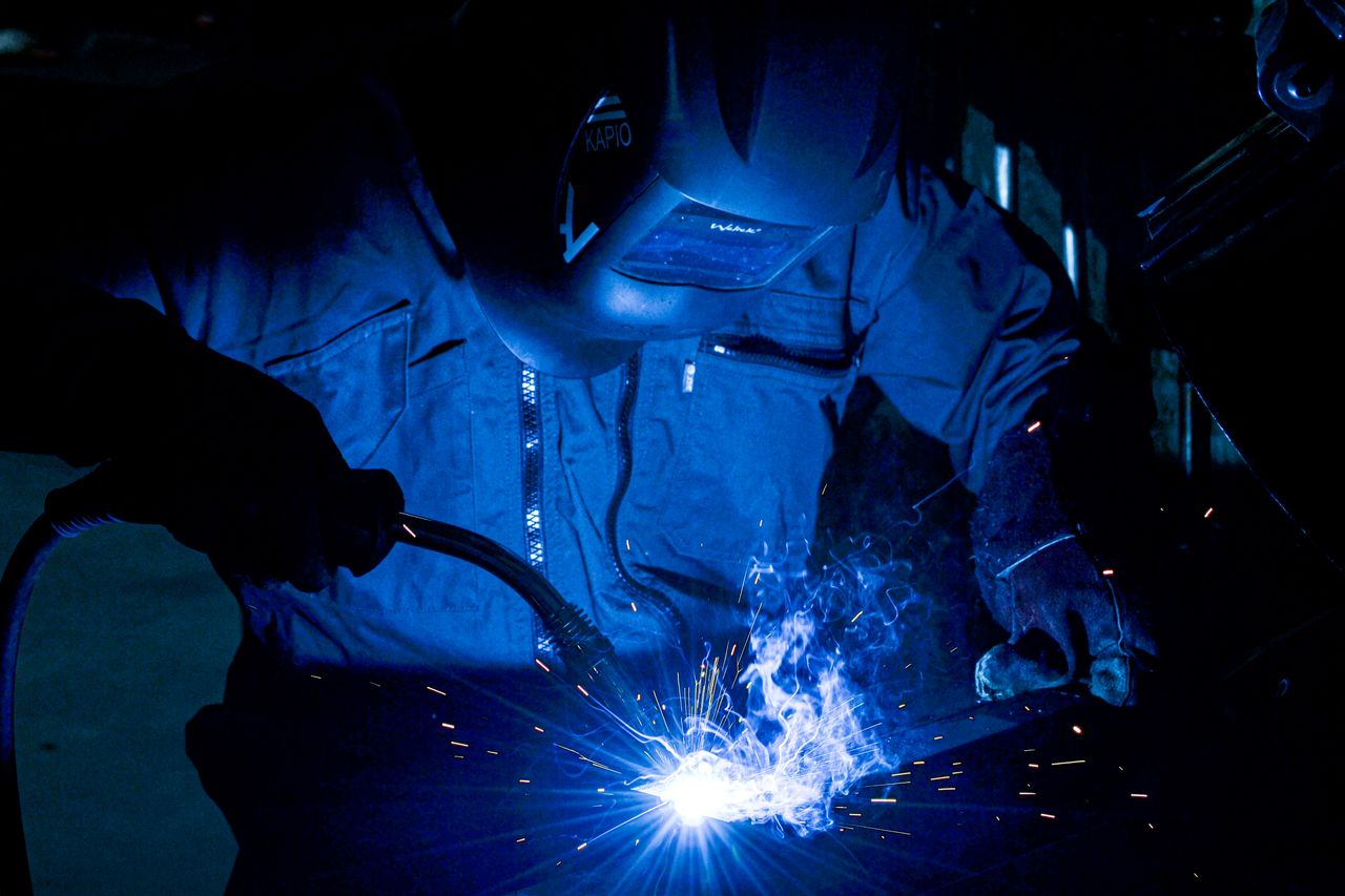Home A welder using protective gear works with intense sparks flying.